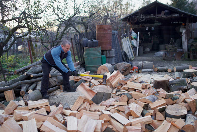 A man splitting a pile of wood with a splitting axe