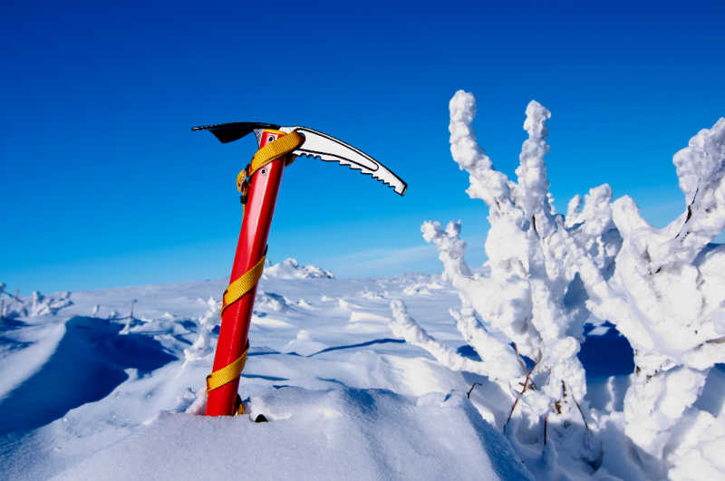A red ice axe in the snow on a fine day
