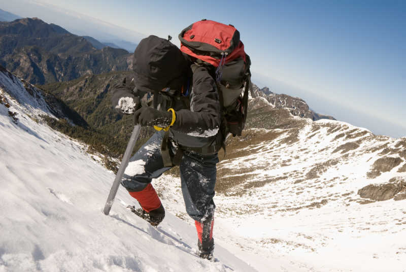 A mountaineer walking through snow using an ice axe for assistance