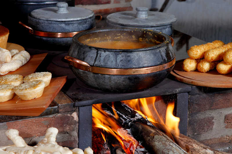 Firewood burning to heat pots of food.