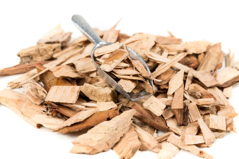 A pile of hickory wood chips and a scoop isolated on white background