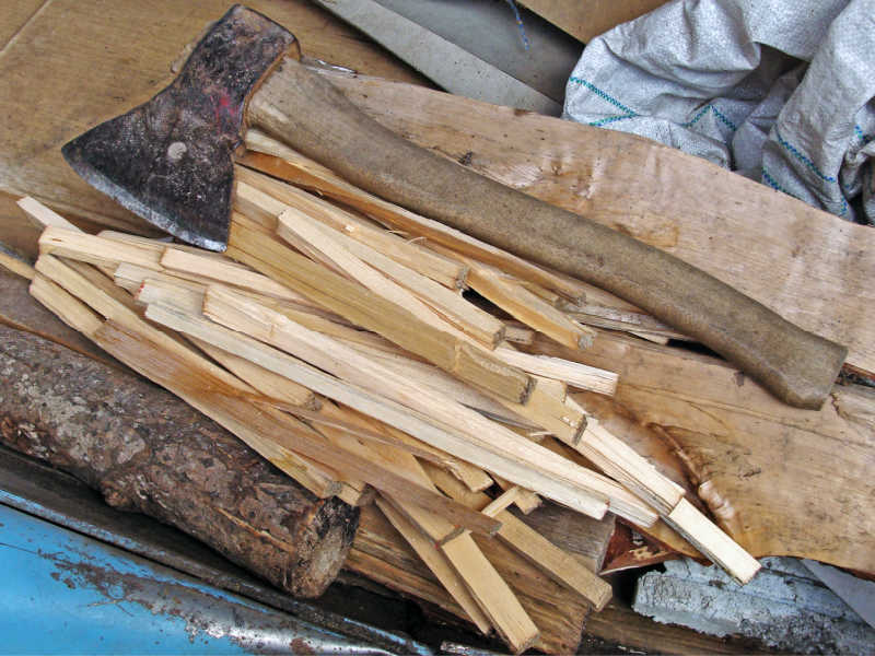 A small pile of split kindling next to a hatchet