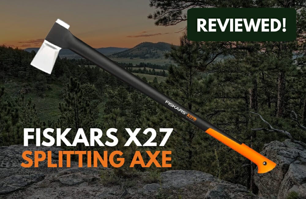 A Fiskars X27 Splitting Axe with forest in the background